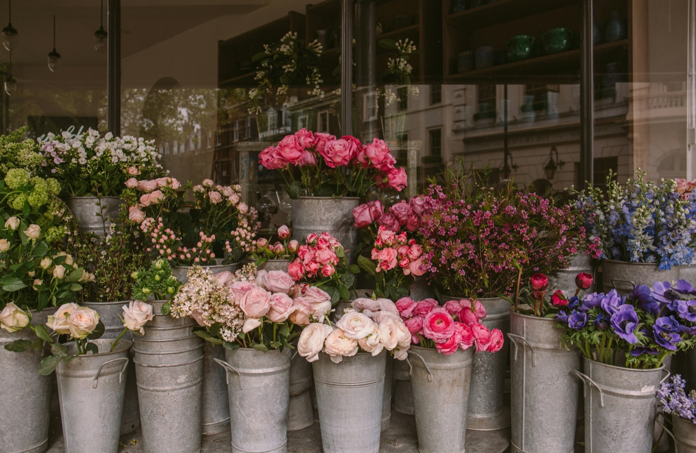 Metal buckets full of fresh flowers outside a flower shop