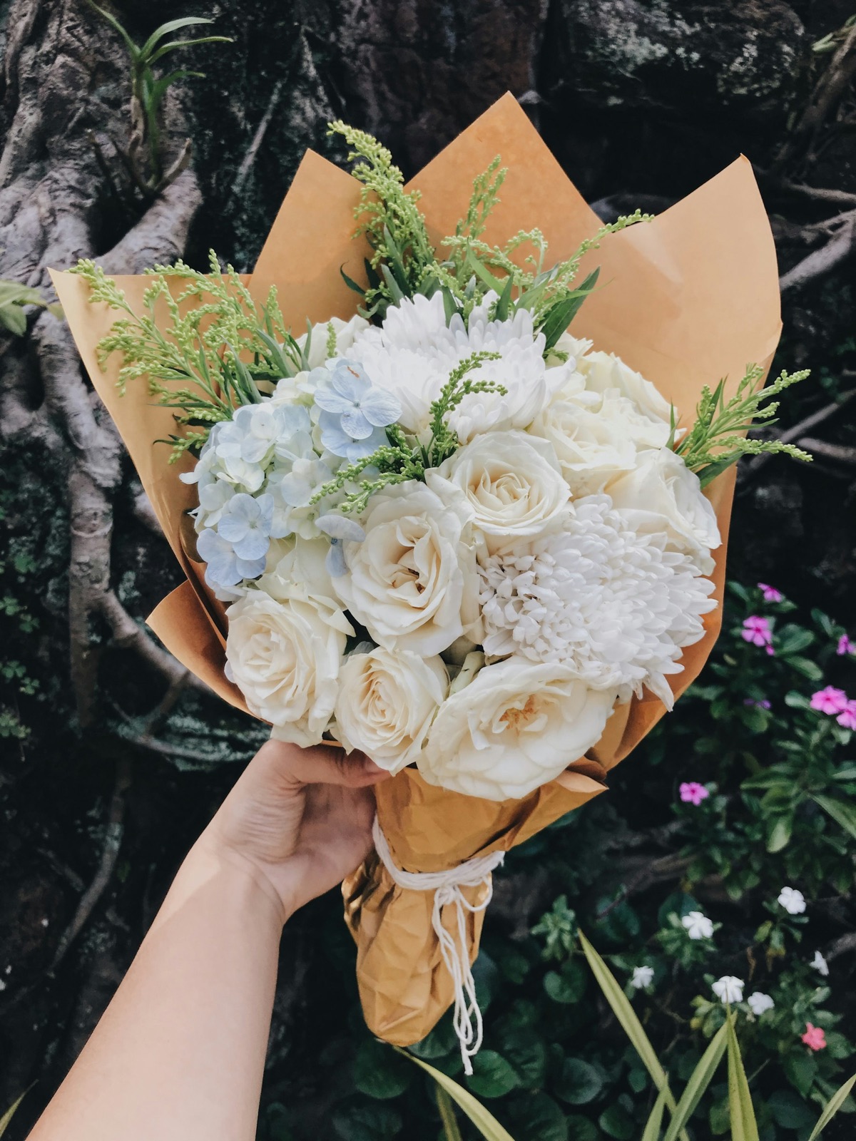White roses, hydrangea and eucalyptus wrapped in kraft paper.