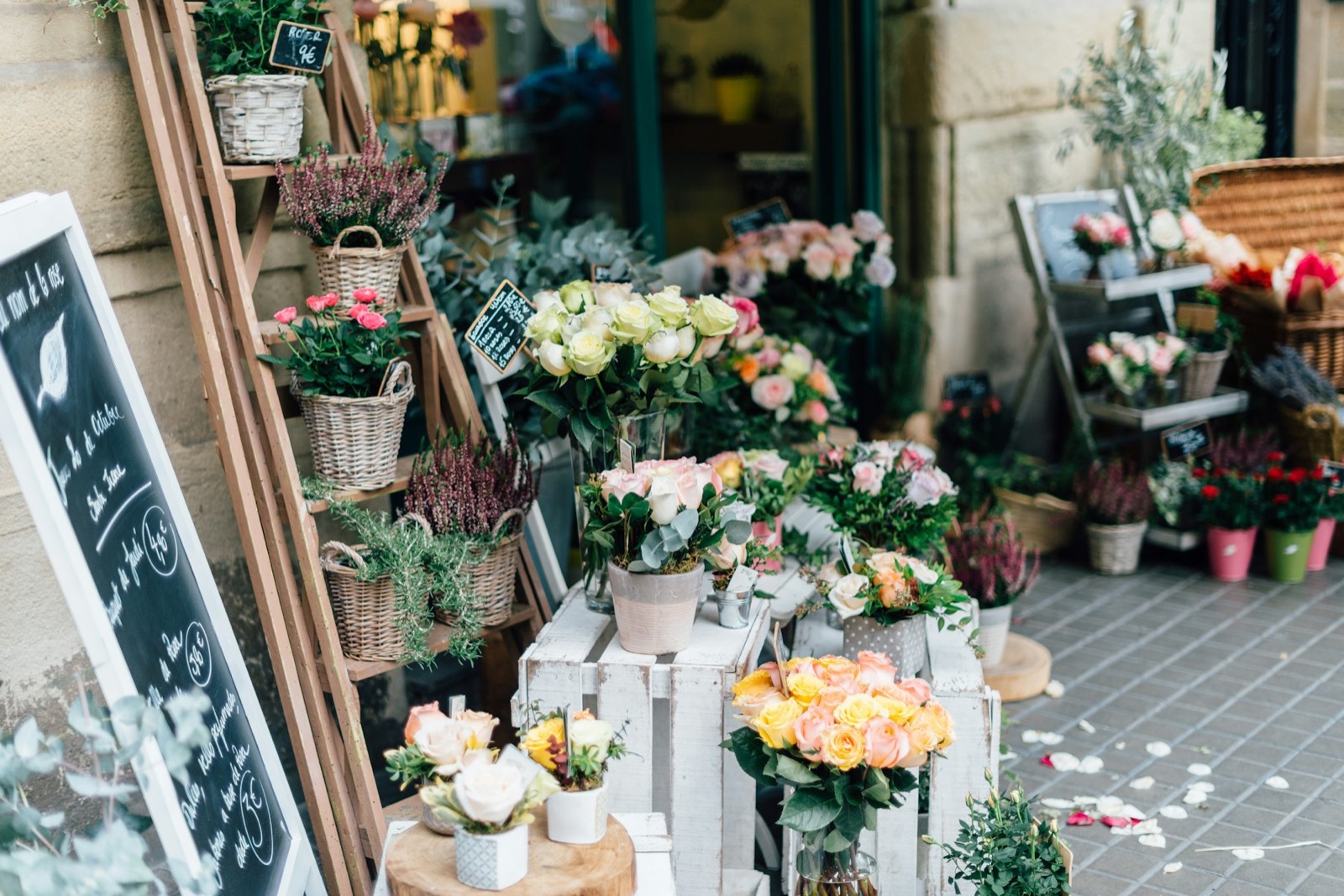 A florist's storefront with buckets of fresh flowers on the pavement